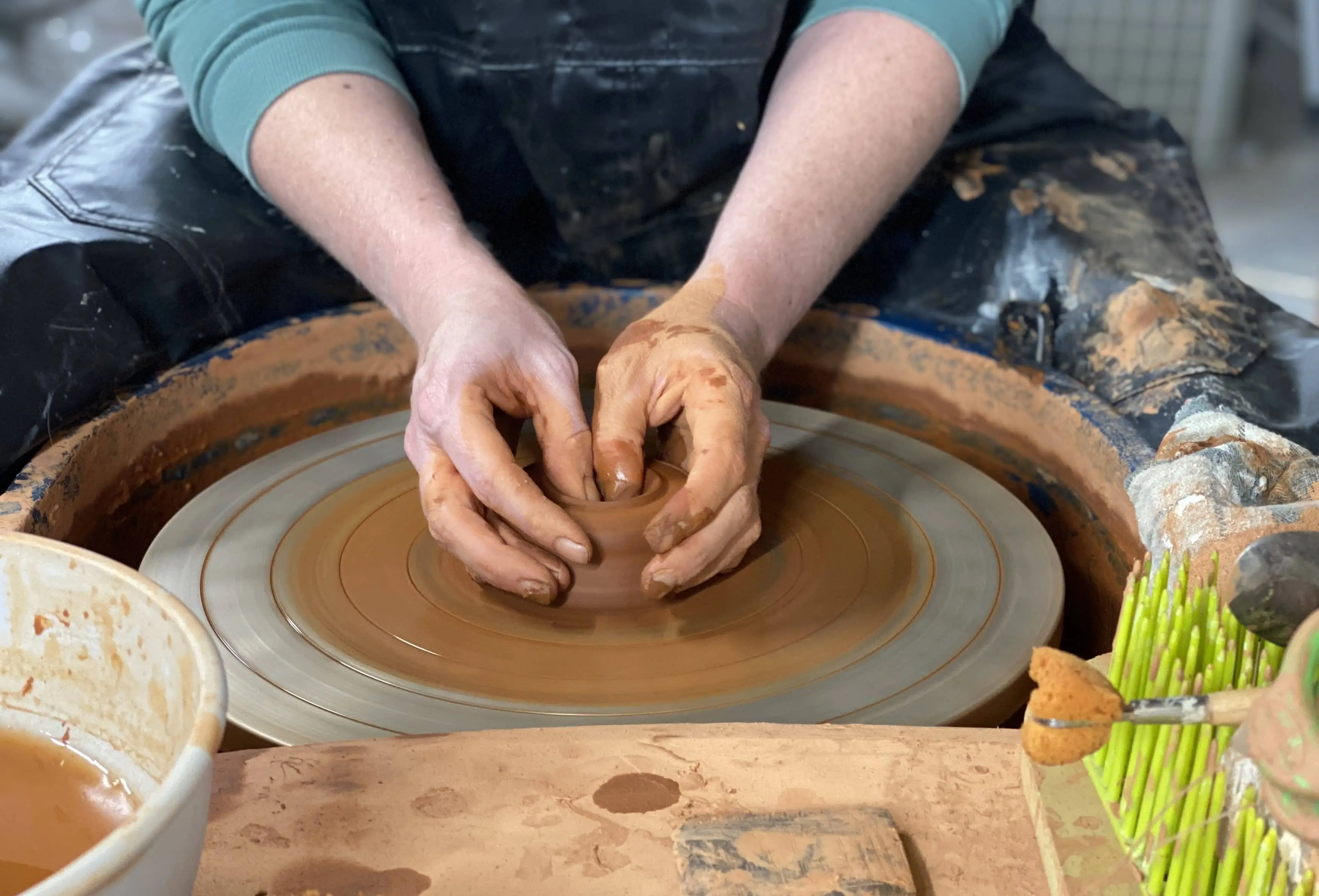 Closeup of a person throwing on the wheel